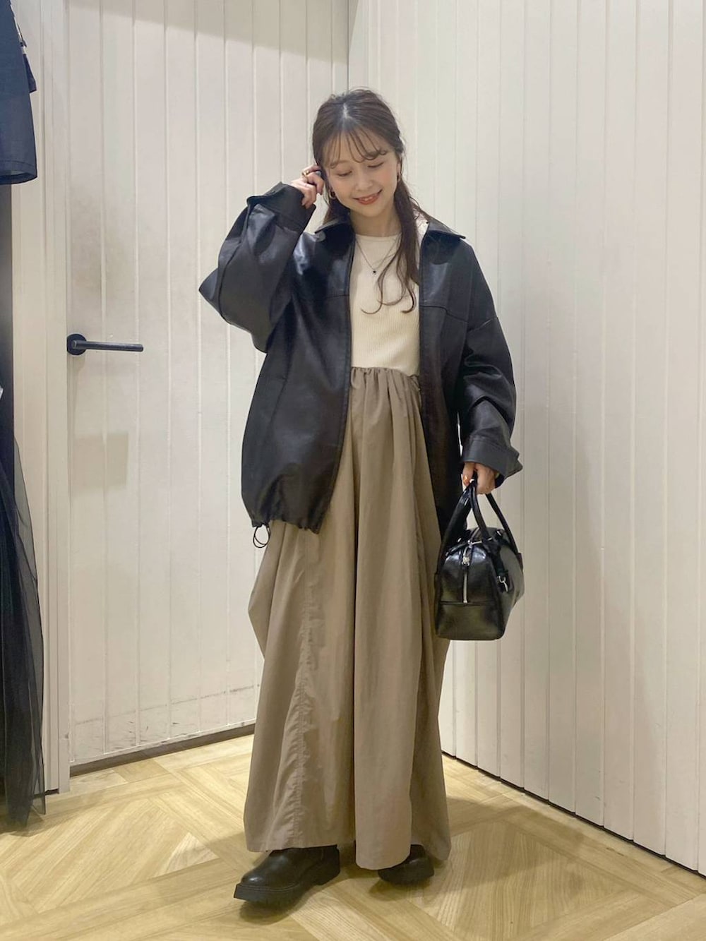 ブラウン系のブルゾン、ブラック系のボストンバッグ、ホワイト系のワンピースを着用したレディースの秋コーディネートの4枚目の写真