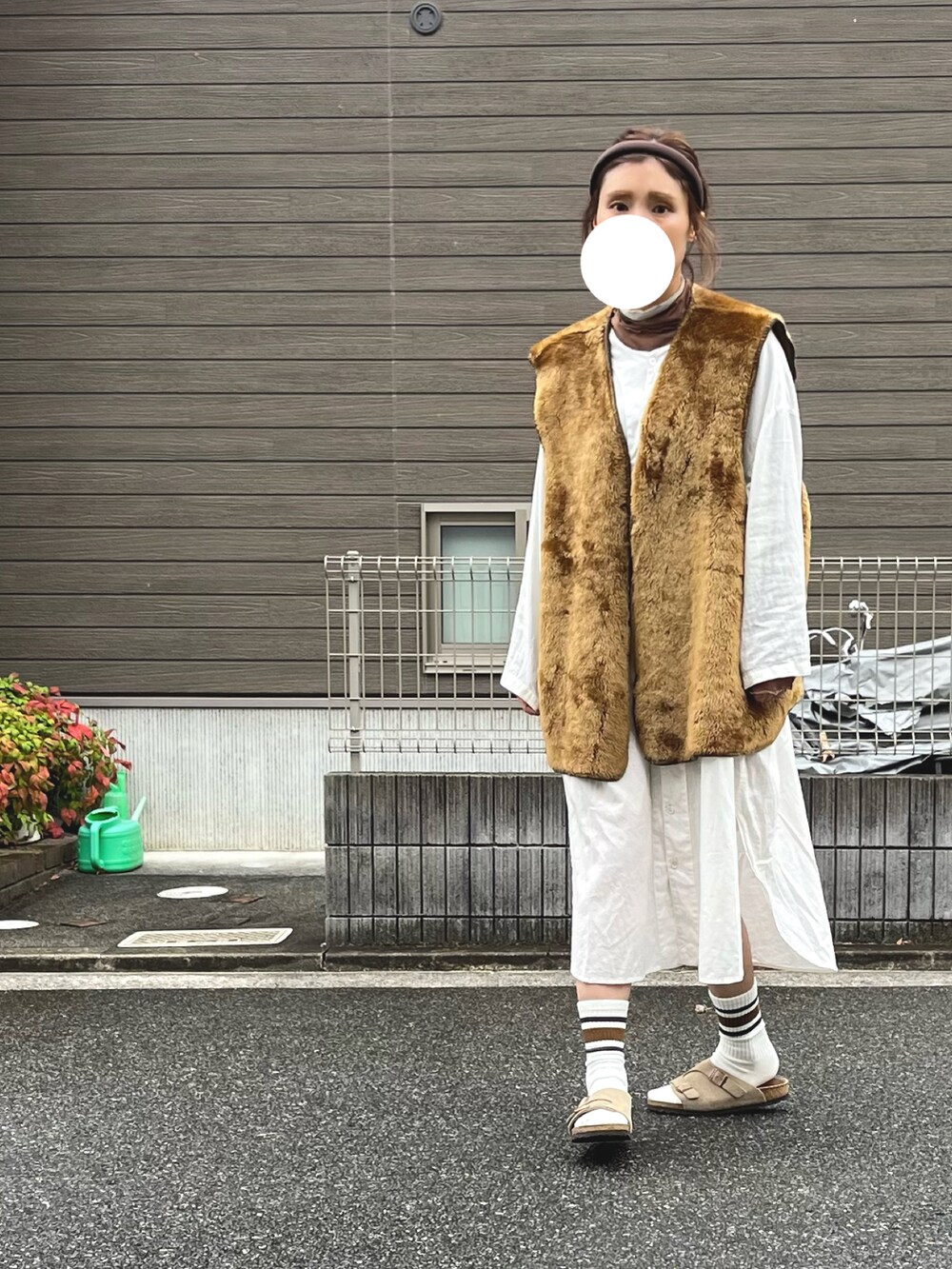 ベージュ系のシャツワンピース、ベージュ系のサンダル、ブラウン系のベストを着用したレディースの秋コーディネートの2枚目の写真