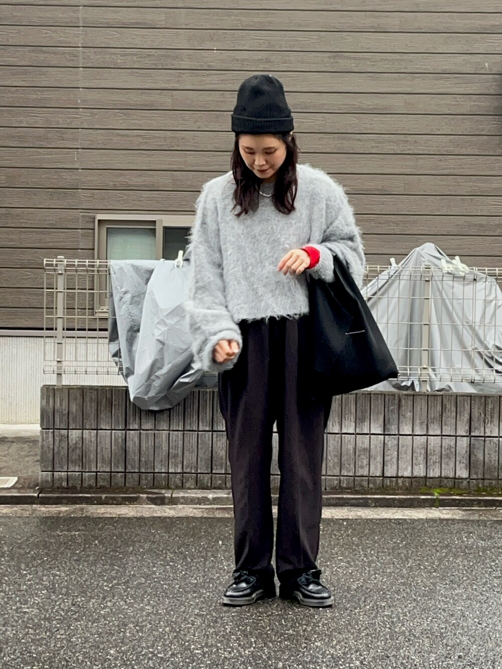 グレー系のニット/セーター、レッド系のTシャツ/カットソー、ブラック系のショルダーバッグを着用したレディースの冬コーディネートの2枚目の写真