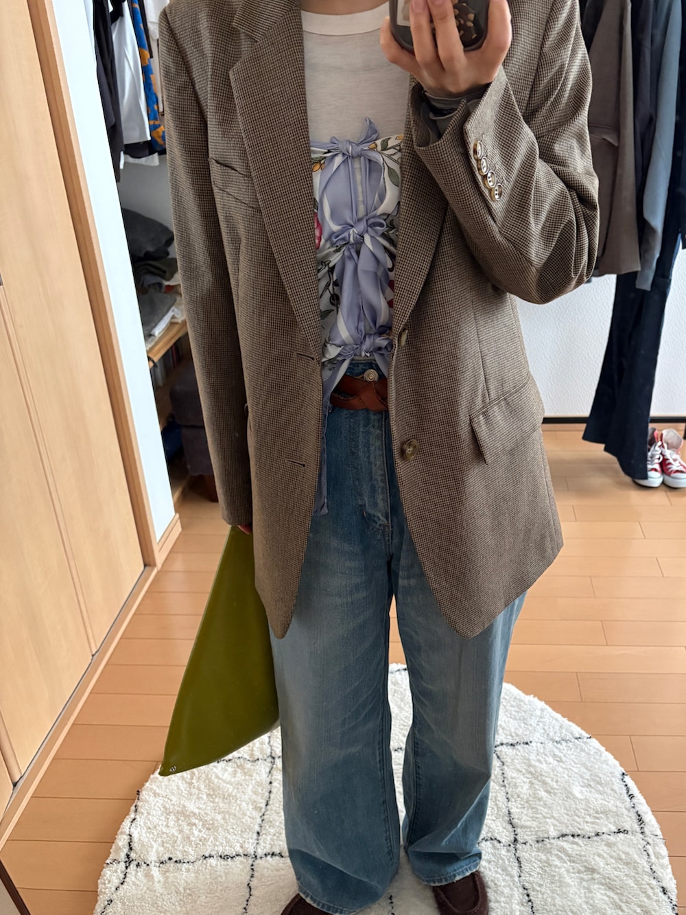 ブルー系のデニムパンツ、ブラウン系のテーラードジャケット、その他のハンドバッグを着用したレディースの春コーディネートの2枚目の写真