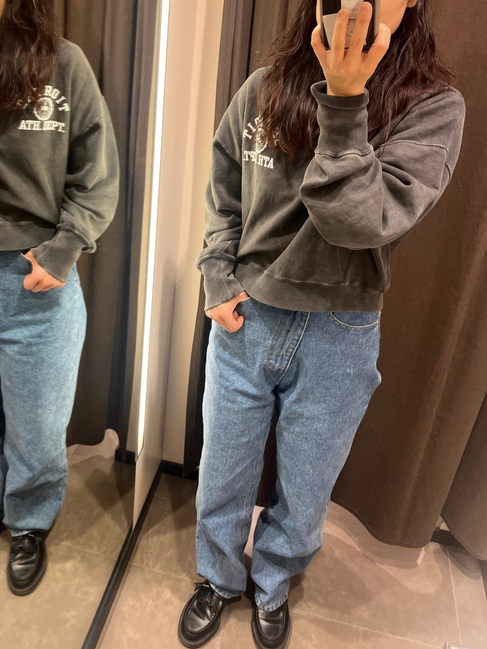 ブラック系のスウェット、ブルー系のデニムパンツ、ブラック系のローファーを着用したレディースの春コーディネートの2枚目の写真