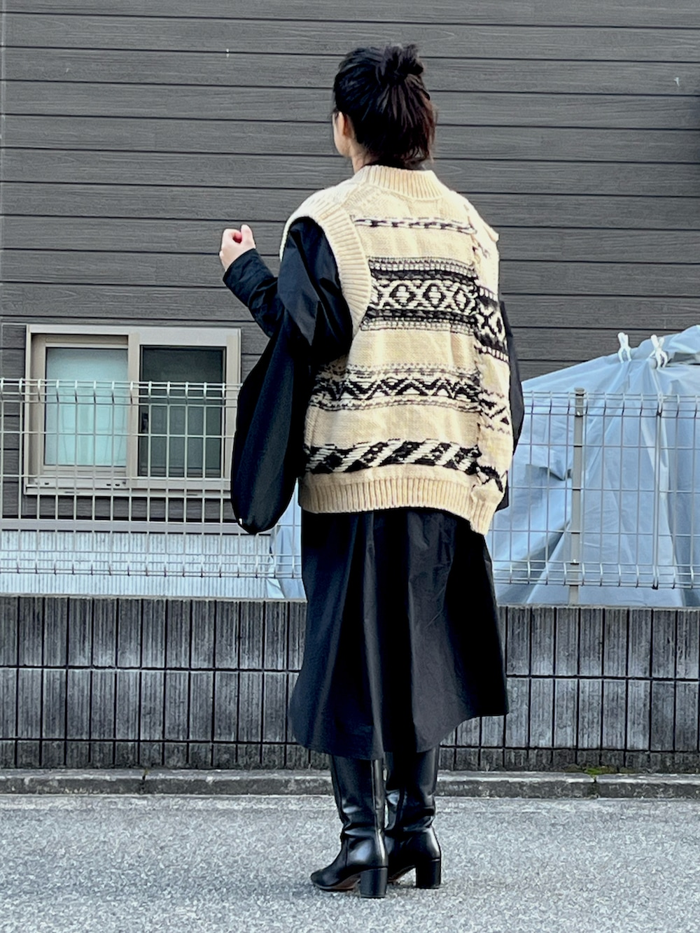 ホワイト系のニット/セーター、ブラック系のブーツ、ブラック系のショルダーバッグを着用したレディースの冬コーディネートの2枚目の写真