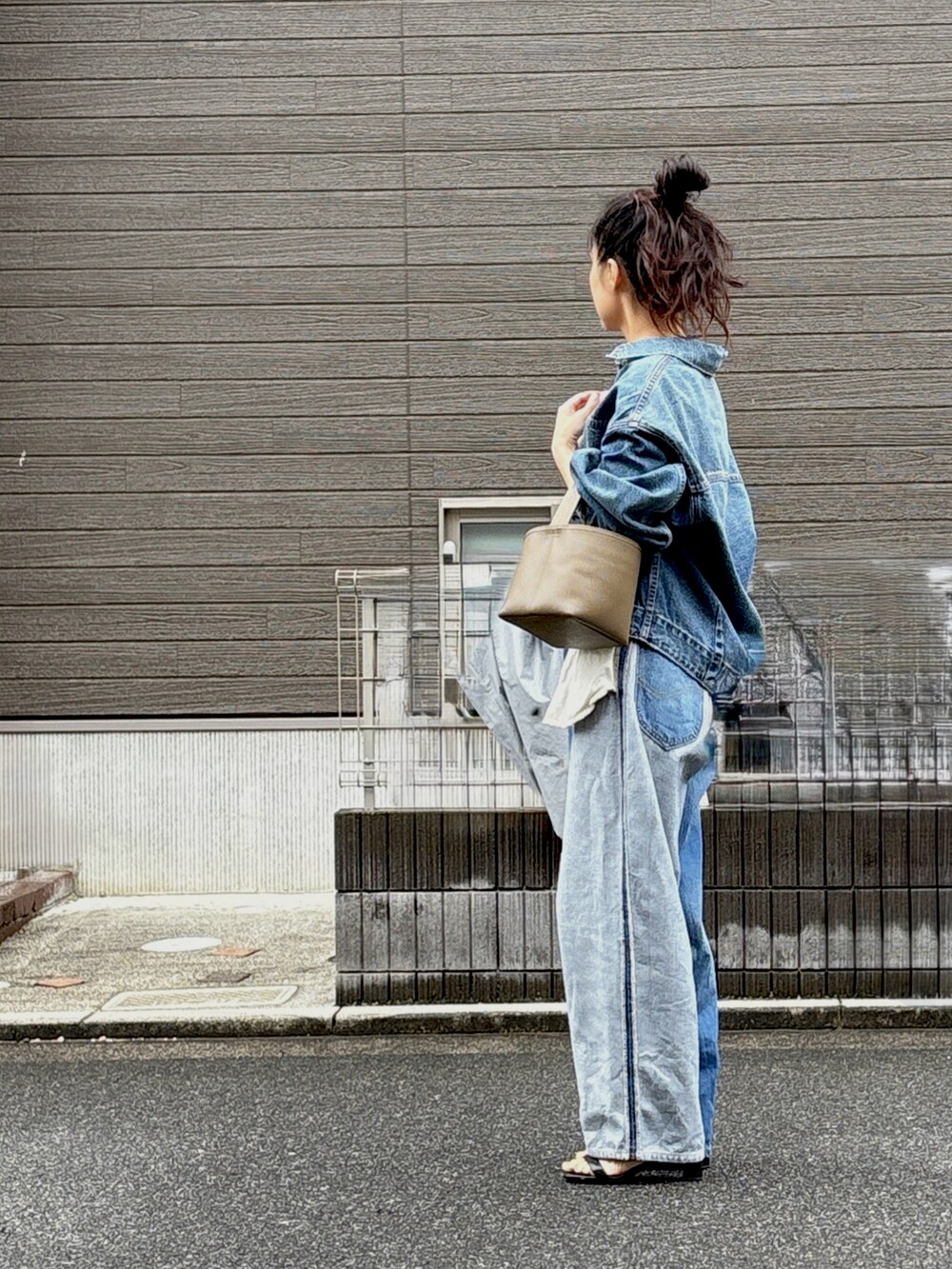 ブルー系のデニムパンツ、ブルー系のデニムジャケット、ブラック系のサンダルを着用したレディースの秋コーディネートの2枚目の写真