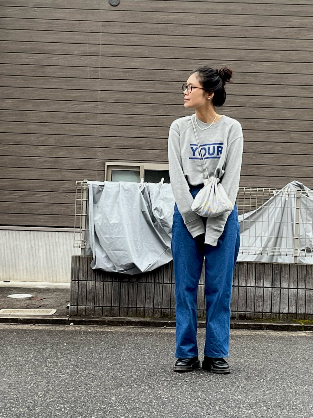 グレー系のTシャツ/カットソー、シルバー系のショルダーバッグ、ブルー系のデニムパンツを着用したレディースの春コーディネートの2枚目の写真