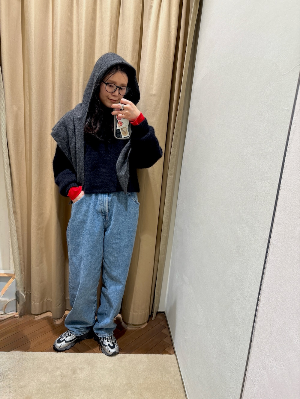 レッド系のTシャツ/カットソー、ブラック系のニット/セーター、ブルー系のデニムパンツを着用したレディースの冬コーディネートの2枚目の写真