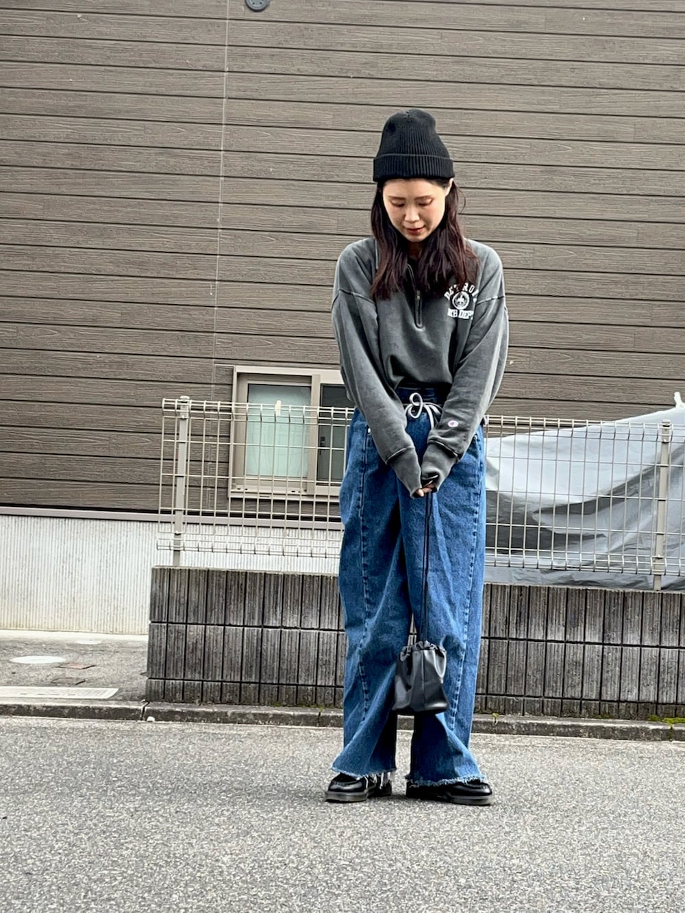 ブラック系のスウェット、ブルー系のデニムパンツ、ブラック系のショルダーバッグを着用したレディースの冬コーディネートの2枚目の写真