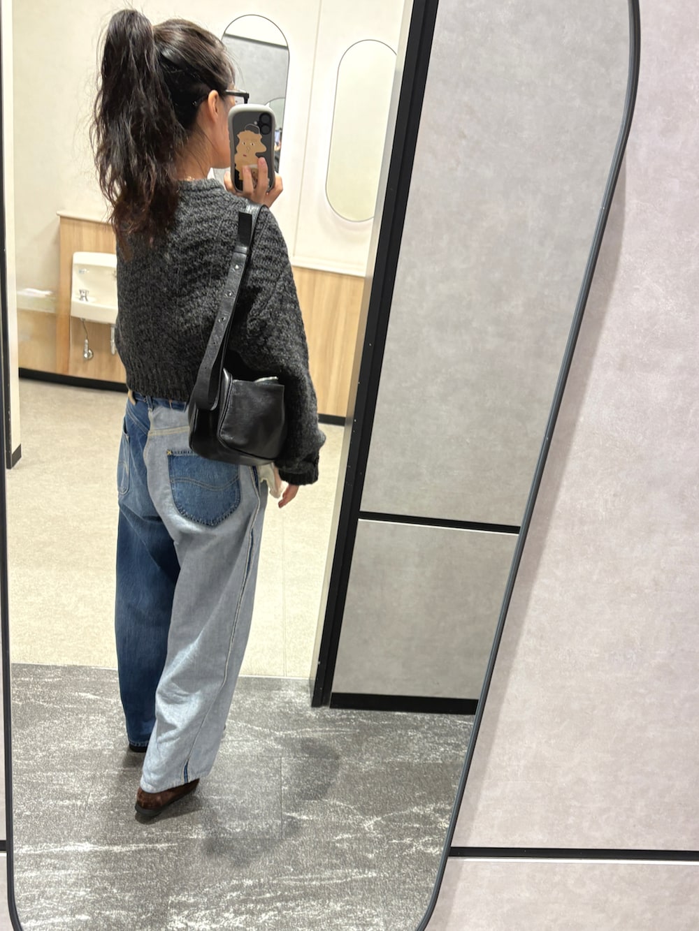 ブルー系のデニムパンツ、ブラウン系のローファー、グレー系のカーディガン/ボレロを着用したレディースの秋コーディネートの2枚目の写真