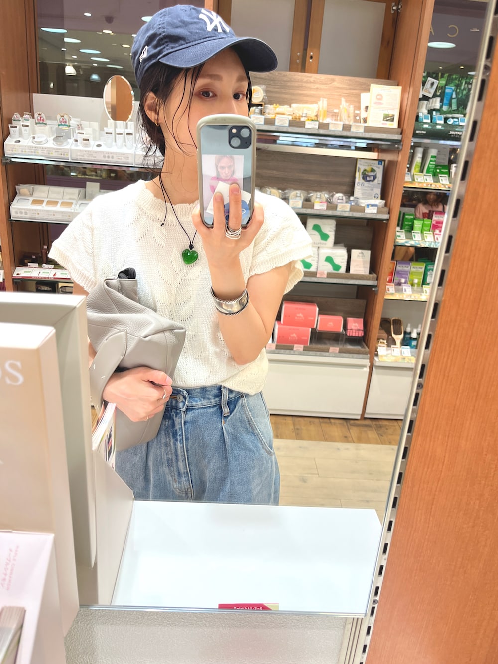 ベージュ系のショルダーバッグ、ブルー系のデニムパンツ、ブルー系のスニーカーを着用したレディースの夏コーディネートの2枚目の写真