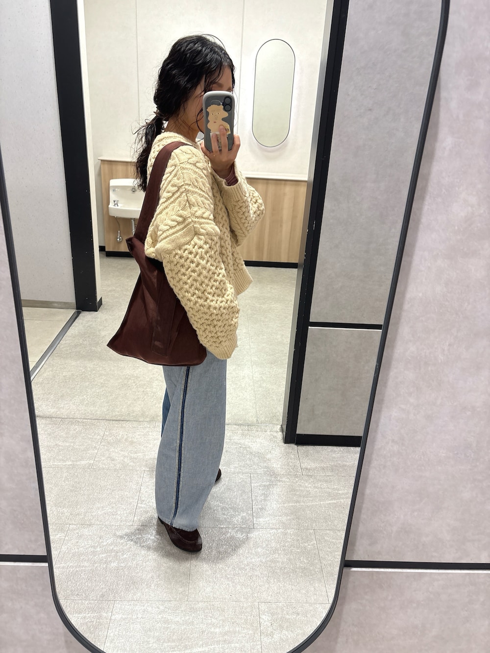 ブルー系のデニムパンツ、ブラウン系のトートバッグ、ブラウン系のローファーを着用したレディースの冬コーディネートの3枚目の写真