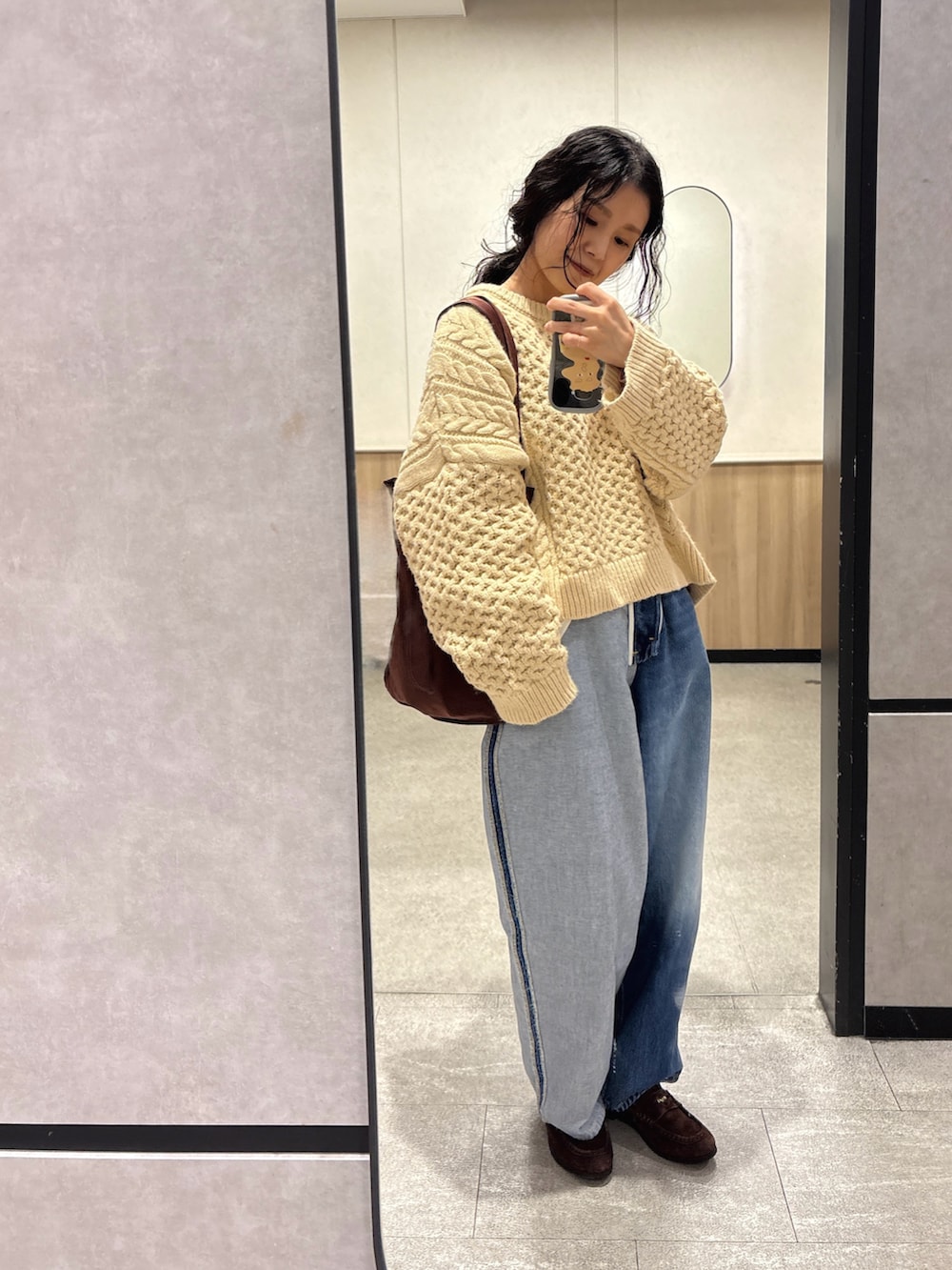 ブルー系のデニムパンツ、ブラウン系のトートバッグ、ブラウン系のローファーを着用したレディースの冬コーディネートの2枚目の写真