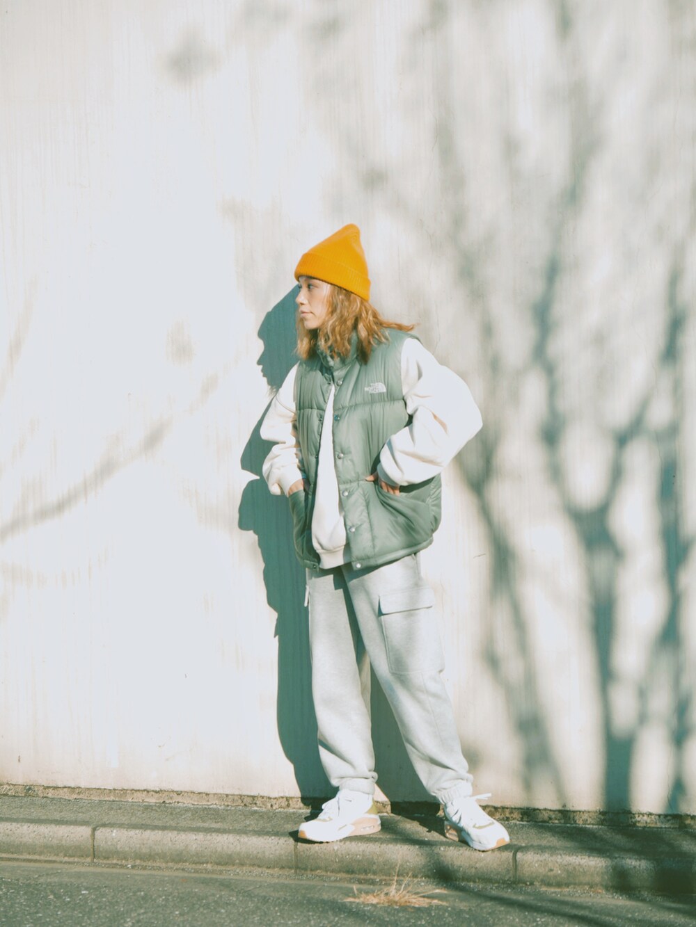 グリーン系のダウンベスト、ホワイト系のスウェット、グレー系のスウェットパンツを着用したレディースの冬コーディネートの4枚目の写真