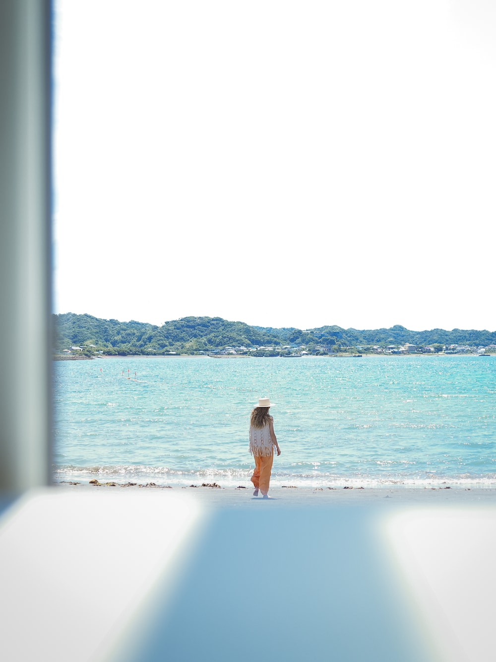 ホワイト系のトップス、オレンジ系のパンツ、ベージュ系のサンダルを着用したレディースの夏コーディネートの4枚目の写真