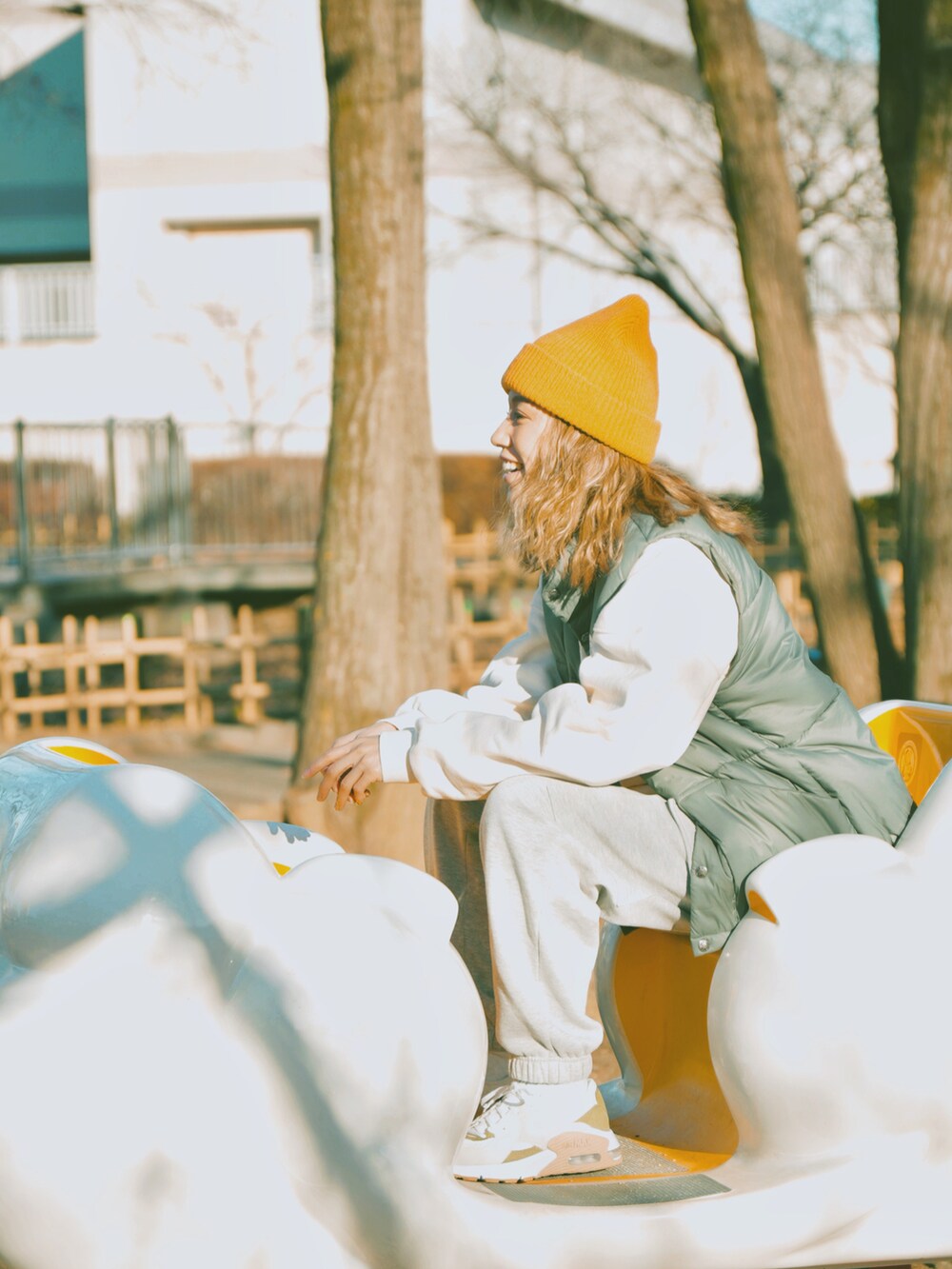 グリーン系のダウンベスト、ホワイト系のスウェット、グレー系のスウェットパンツを着用したレディースの冬コーディネートの2枚目の写真