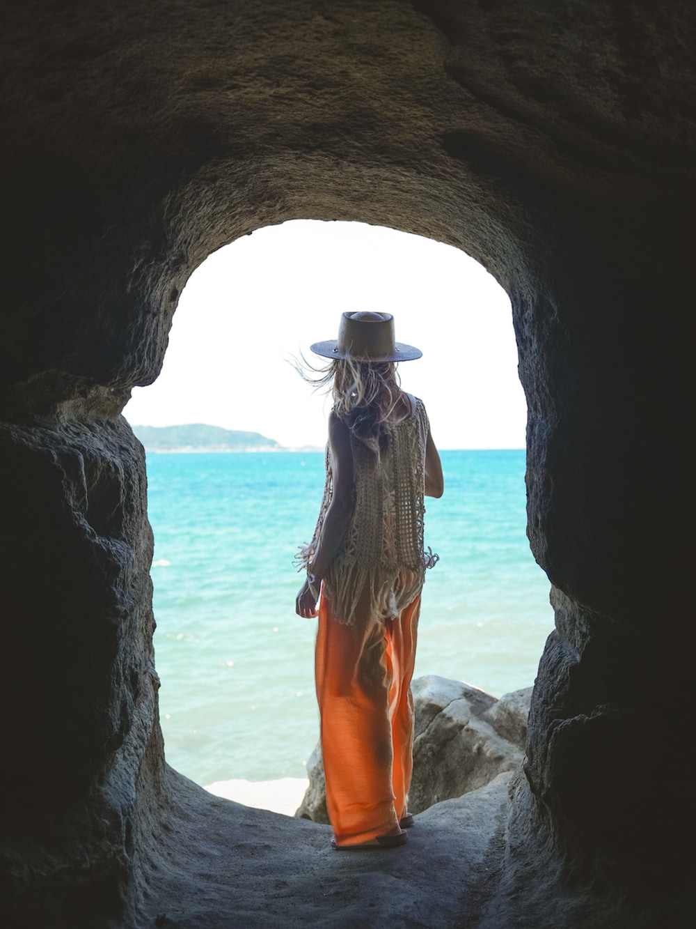 ホワイト系のトップス、オレンジ系のパンツ、ベージュ系のサンダルを着用したレディースの夏コーディネートの2枚目の写真