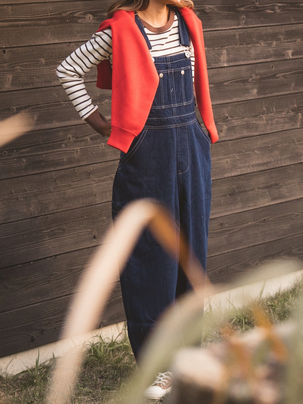 ブラウン系のTシャツ/カットソー、レッド系のニット/セーター、ブルー系のサロペット/オーバーオールを着用したレディースの冬コーディネートの2枚目の写真