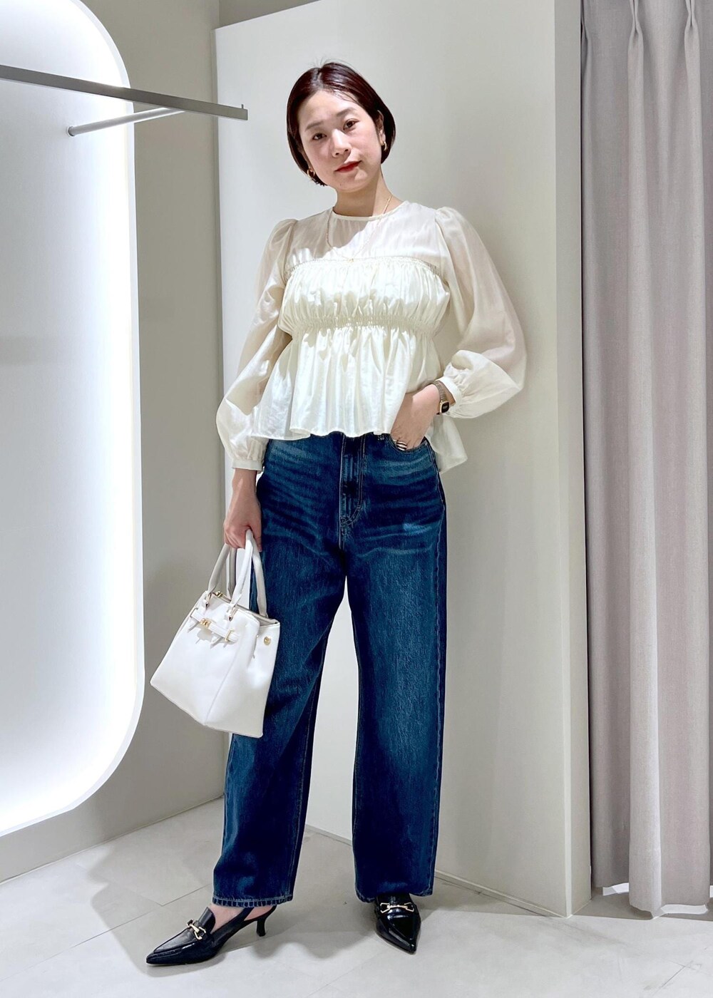 ブラック系のパンプス、ベージュ系のシャツ/ブラウス、ブルー系のデニムパンツを着用したレディースの春コーディネートの2枚目の写真