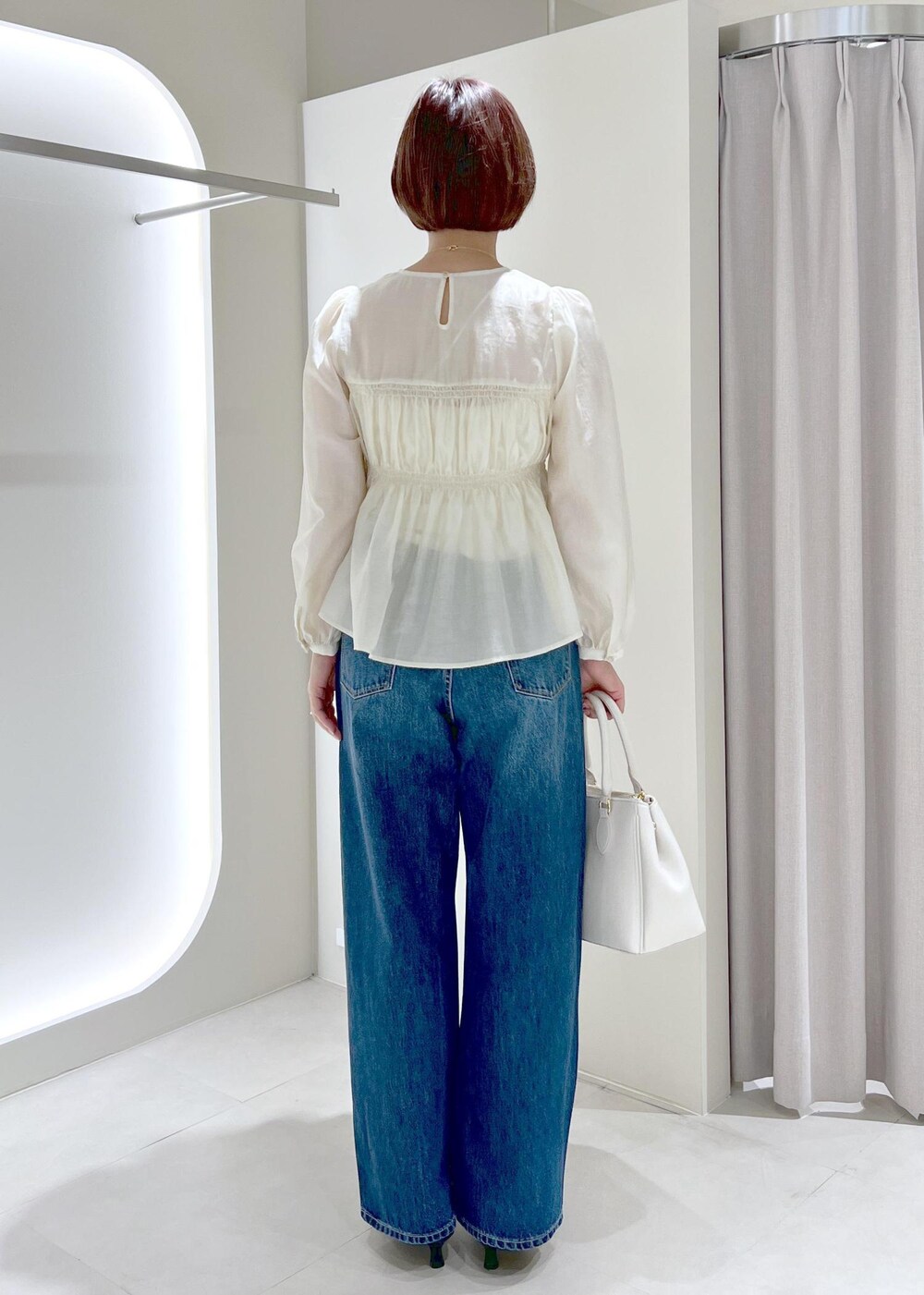 ブラック系のパンプス、ベージュ系のシャツ/ブラウス、ブルー系のデニムパンツを着用したレディースの春コーディネートの5枚目の写真