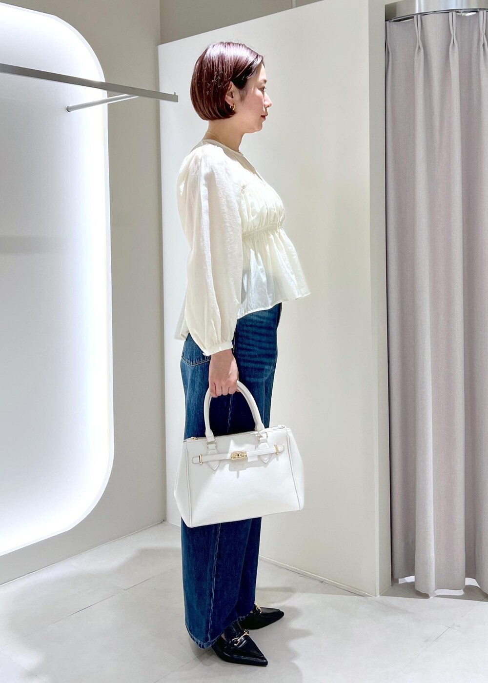 ブラック系のパンプス、ベージュ系のシャツ/ブラウス、ブルー系のデニムパンツを着用したレディースの春コーディネートの4枚目の写真