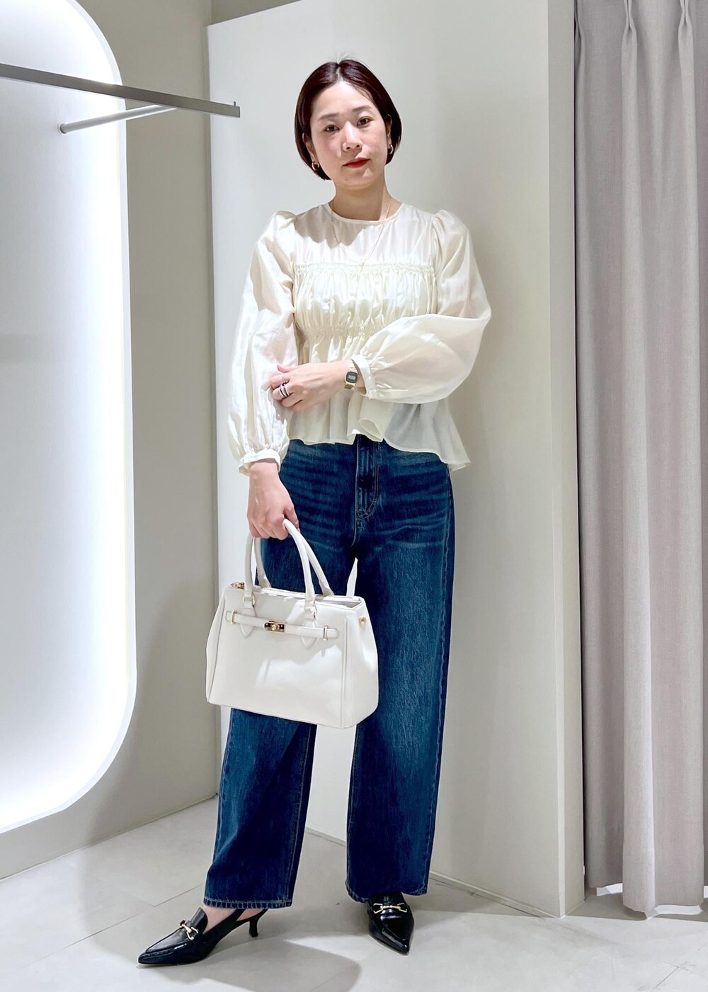 ブラック系のパンプス、ベージュ系のシャツ/ブラウス、ブルー系のデニムパンツを着用したレディースの春コーディネートの3枚目の写真