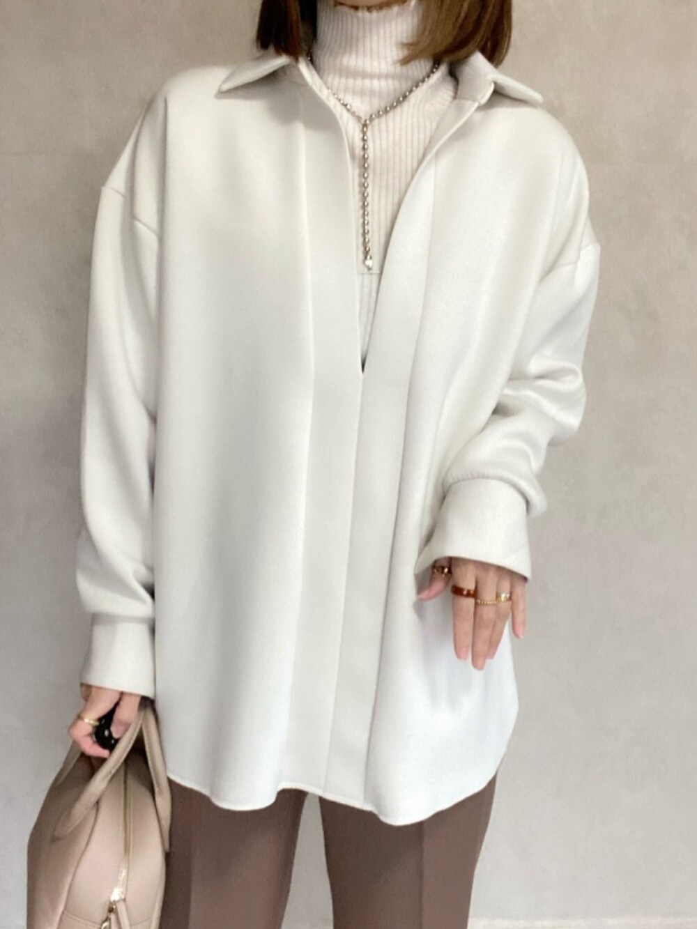 ホワイト系のシャツ/ブラウス、ブラウン系のスラックス、ベージュ系のトートバッグを着用したレディースの冬コーディネートの2枚目の写真