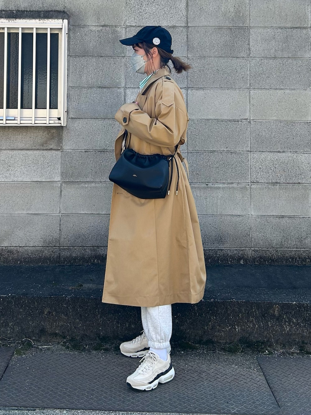ベージュ系のトレンチコート、ブラック系のショルダーバッグ、ベージュ系のスニーカーを着用したレディースの春コーディネートの2枚目の写真