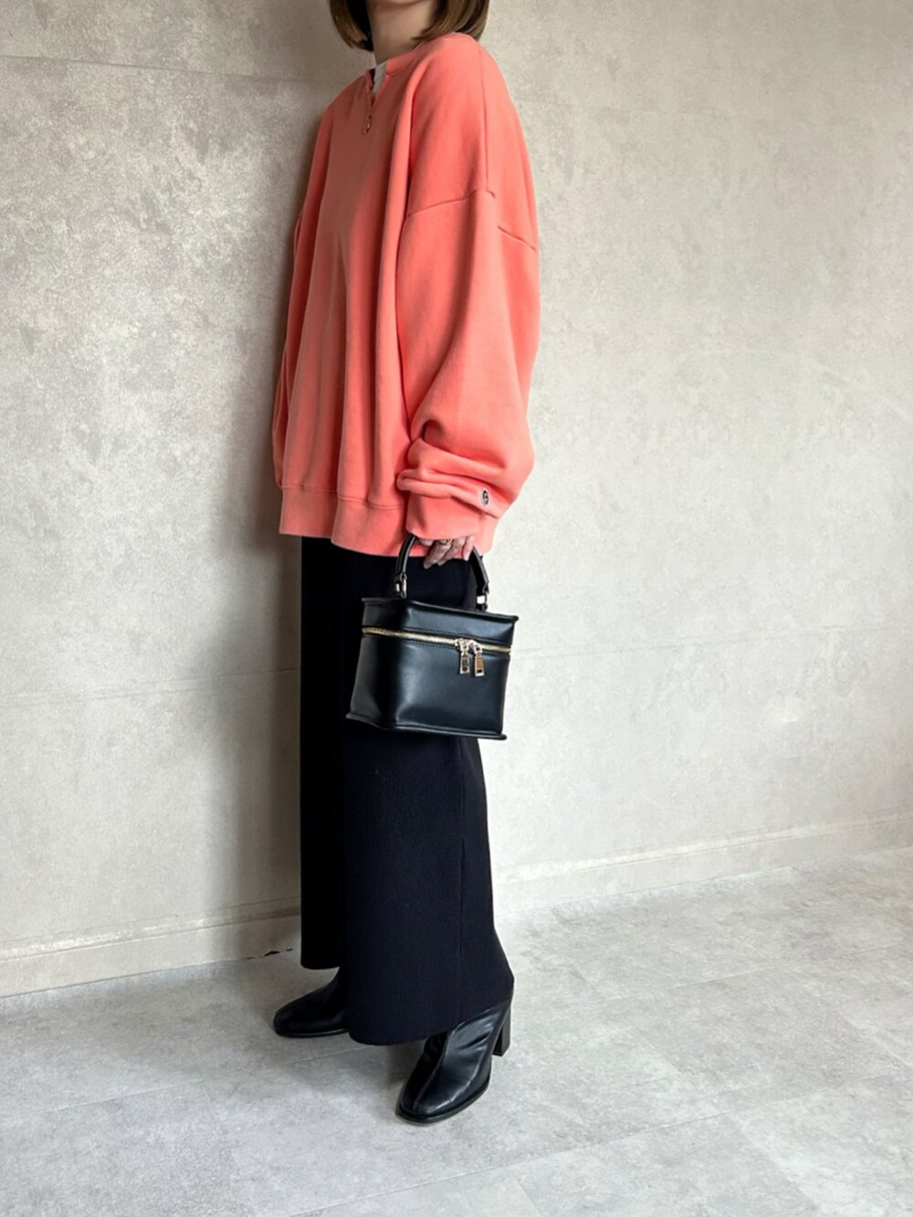 オレンジ系のスウェット、ブラック系のショルダーバッグを着用したレディースの春コーディネートの2枚目の写真
