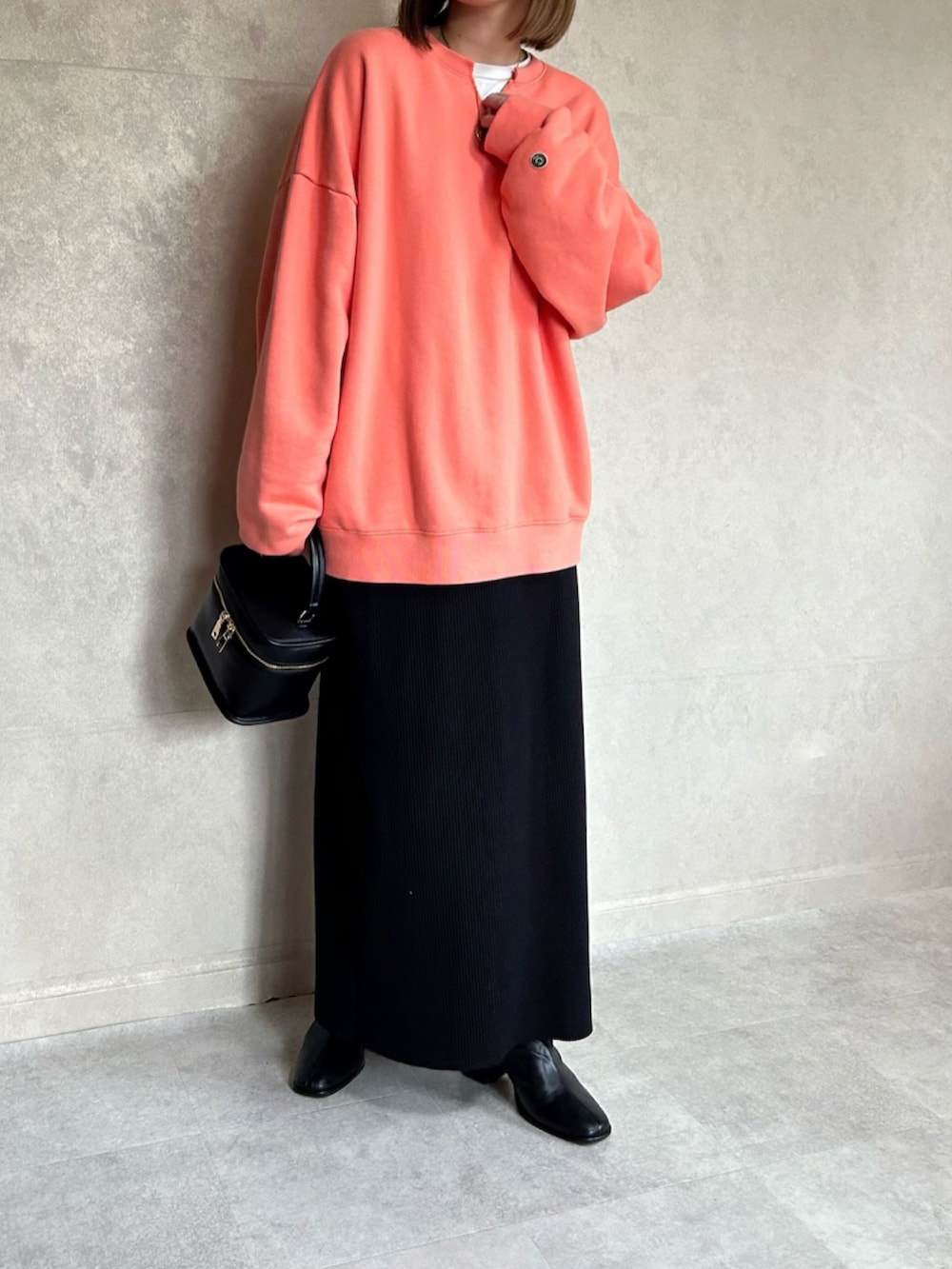 オレンジ系のスウェット、ブラック系のショルダーバッグを着用したレディースの春コーディネートの3枚目の写真