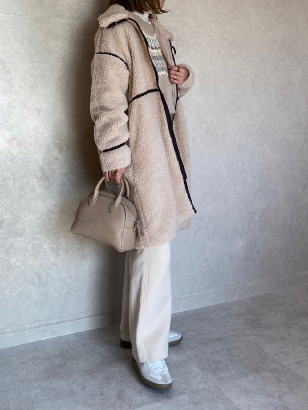 ベージュ系のムートンコート、ブラウン系のニット/セーター、ベージュ系のトートバッグを着用したレディースの冬コーディネートの2枚目の写真