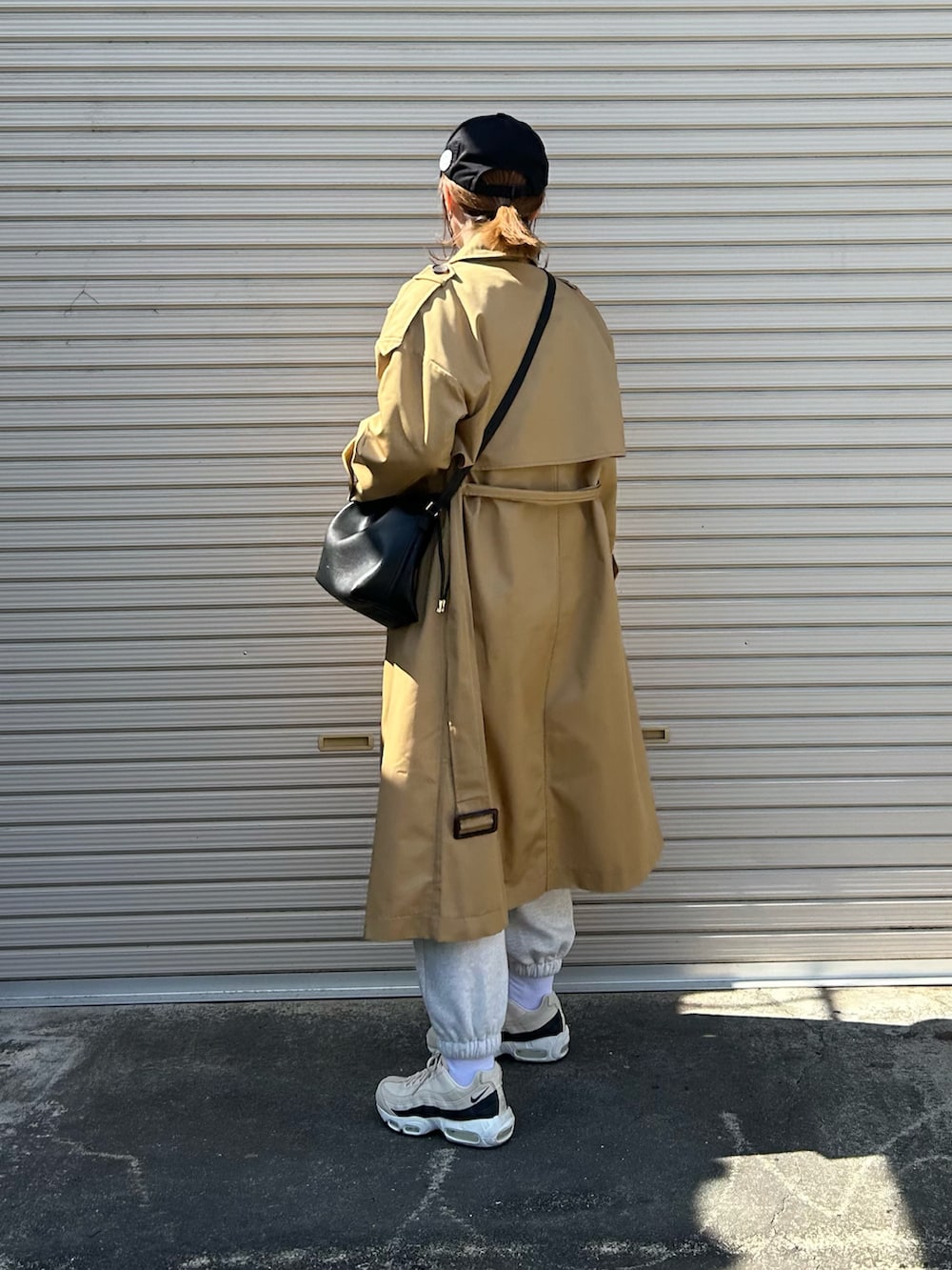 ベージュ系のトレンチコート、ブラック系のショルダーバッグ、ベージュ系のスニーカーを着用したレディースの春コーディネートの5枚目の写真
