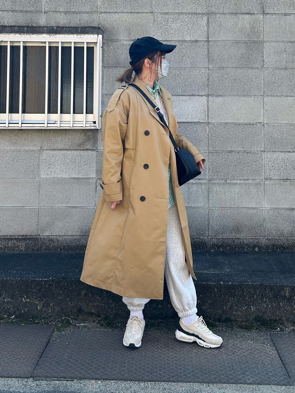 ベージュ系のトレンチコート、ブラック系のショルダーバッグ、ベージュ系のスニーカーを着用したレディースの春コーディネートの4枚目の写真