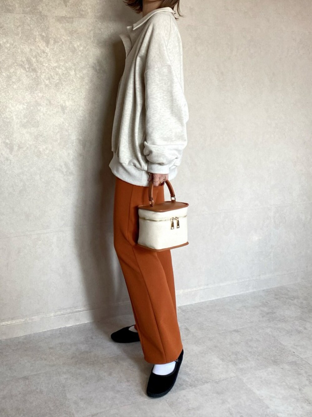 ブラウン系のショルダーバッグ、オレンジ系のスラックス、ブラック系のその他シューズを着用したレディースの春コーディネートの2枚目の写真
