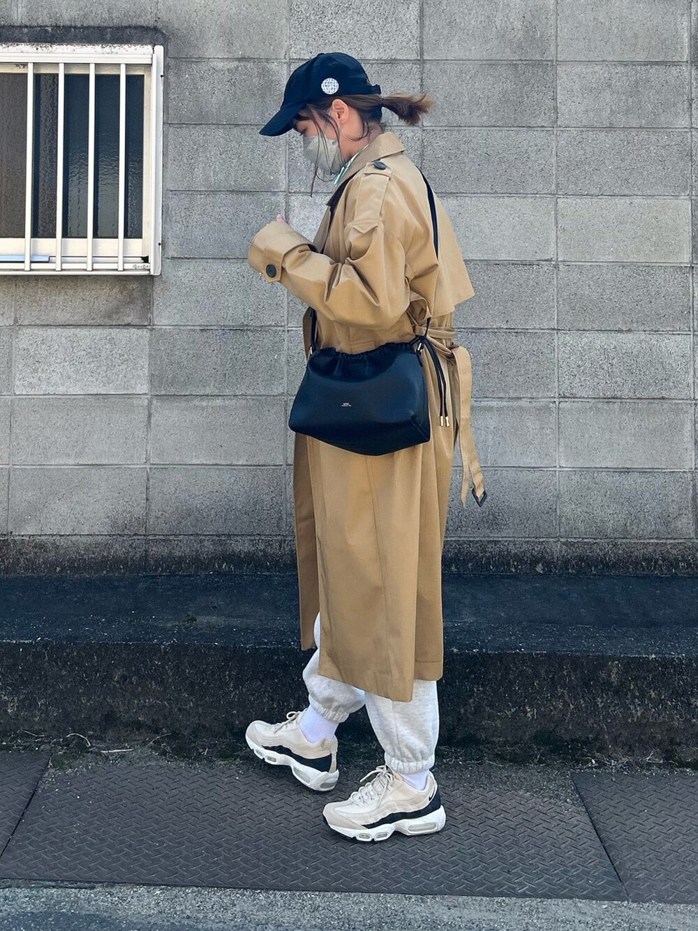 ベージュ系のトレンチコート、ブラック系のショルダーバッグ、ベージュ系のスニーカーを着用したレディースの春コーディネートの3枚目の写真