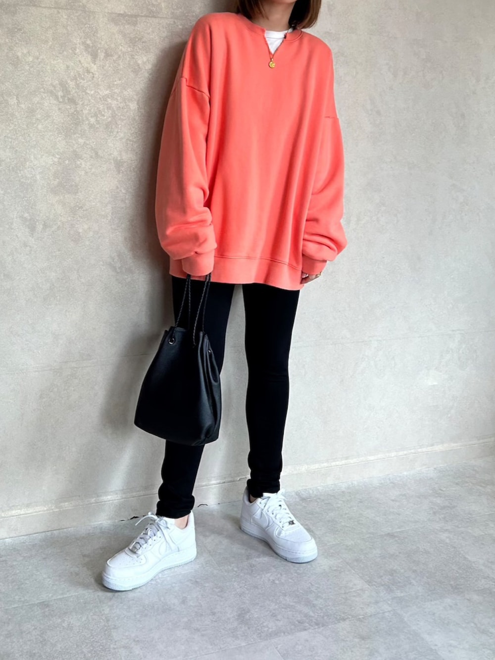 オレンジ系のスウェット、ブラック系のショルダーバッグ、ホワイト系のスニーカーを着用したレディースの春コーディネートの3枚目の写真