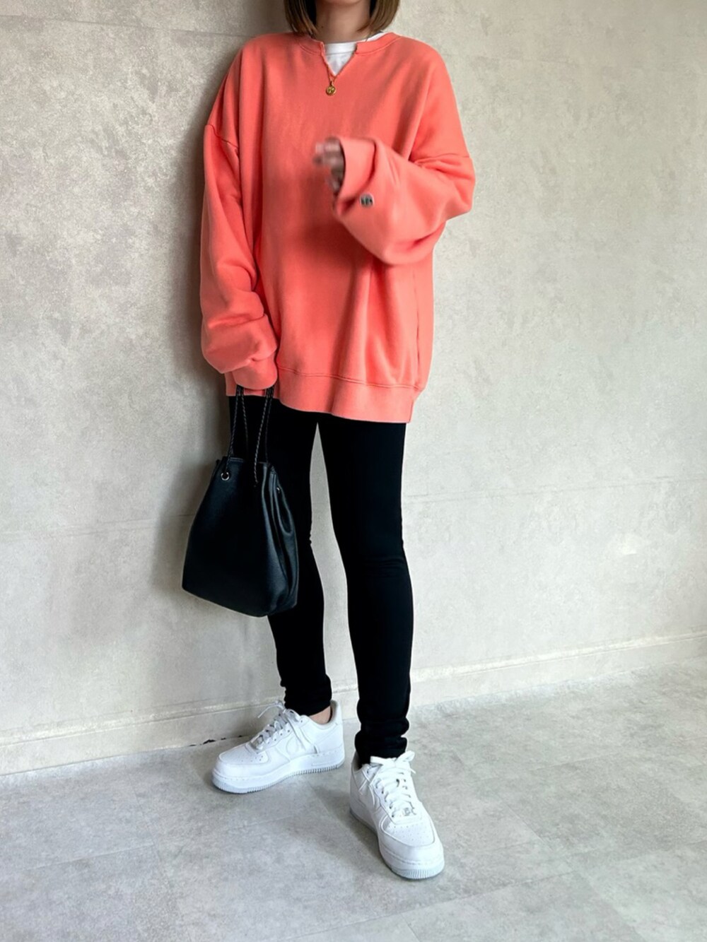 オレンジ系のスウェット、ブラック系のショルダーバッグ、ホワイト系のスニーカーを着用したレディースの春コーディネートの2枚目の写真