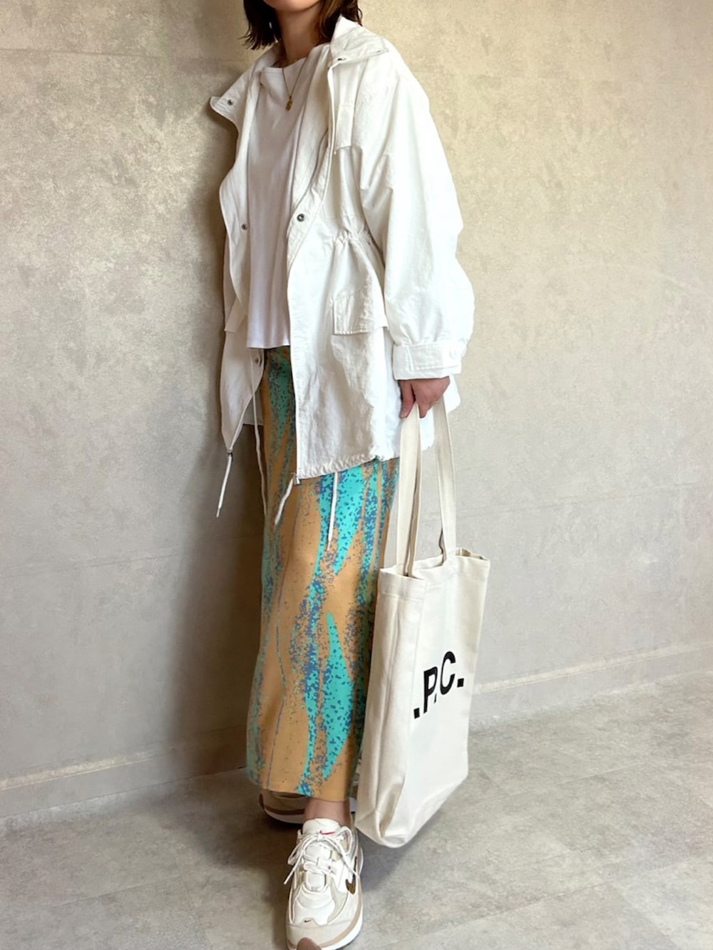 ホワイト系のモッズコート、オレンジ系のスカート、ベージュ系のスニーカーを着用したレディースの春コーディネートの3枚目の写真