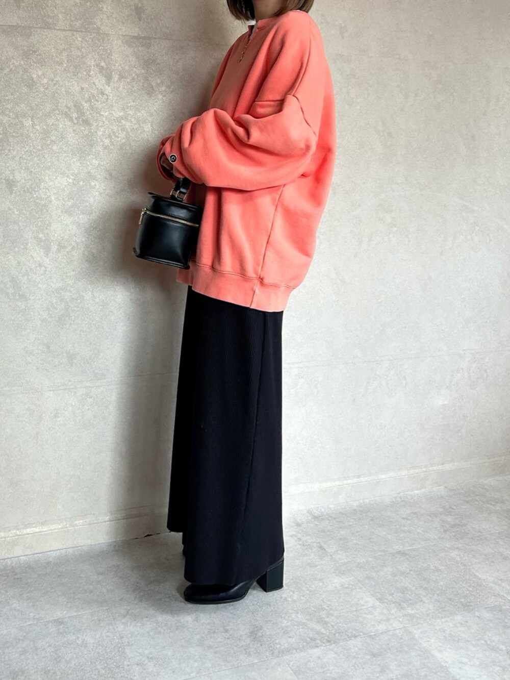 オレンジ系のスウェット、ブラック系のショルダーバッグを着用したレディースの春コーディネートの5枚目の写真