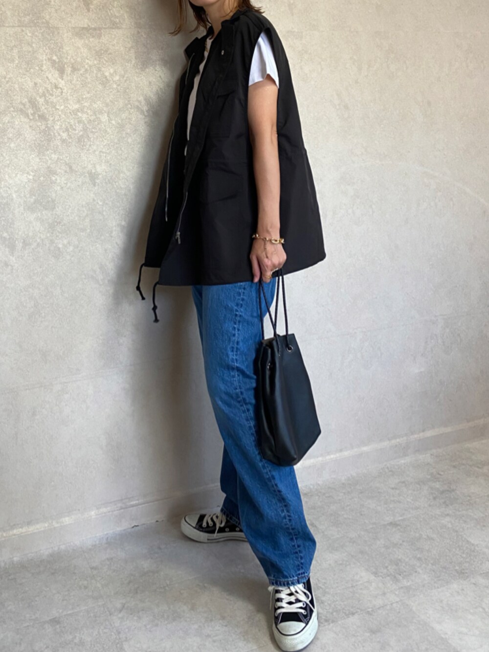 ブラック系のベスト、ブルー系のパンツ、ブラック系のショルダーバッグを着用したレディースの秋コーディネートの2枚目の写真