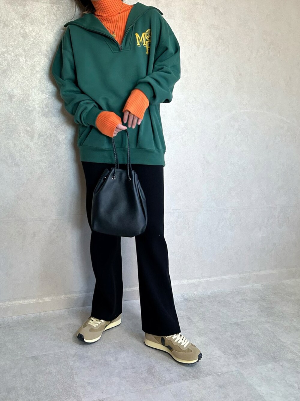 グリーン系のスウェット、オレンジ系のニット/セーター、ブラック系のショルダーバッグを着用したレディースの秋コーディネートの3枚目の写真