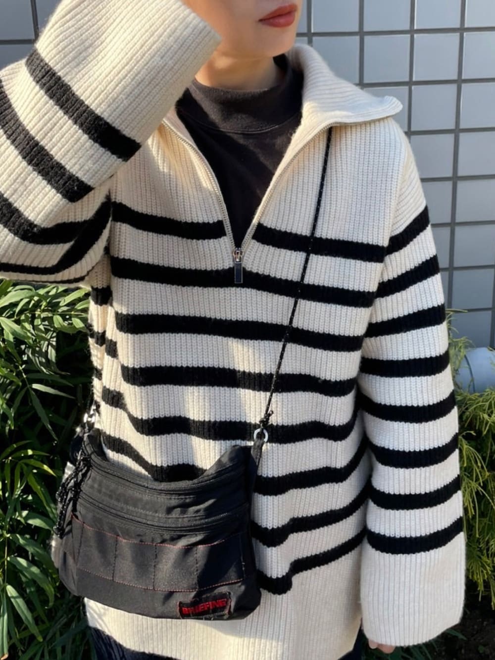 ホワイト系のニット/セーター、ブラック系のショルダーバッグを着用したレディースの秋コーディネートの2枚目の写真