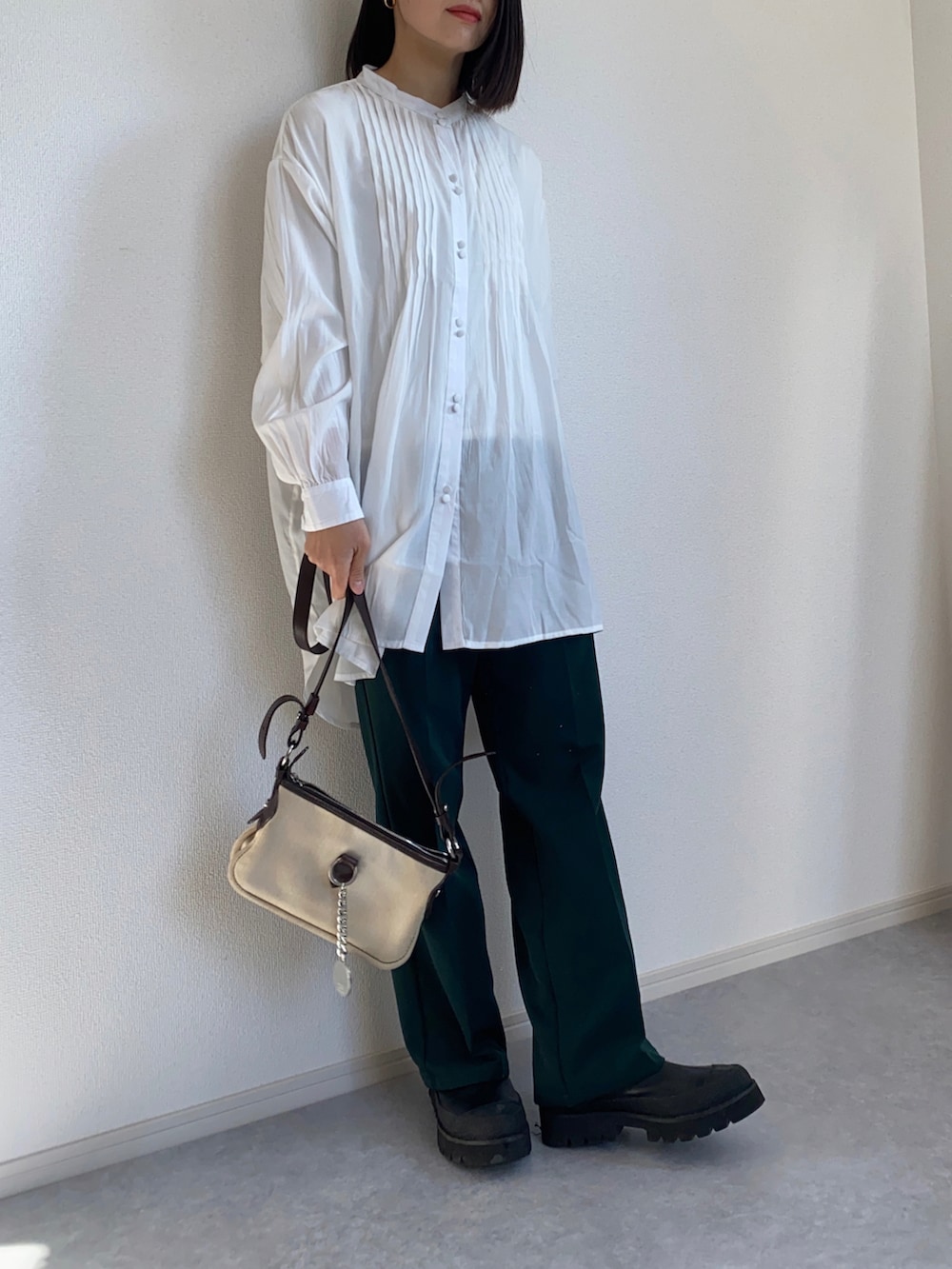 グリーン系のスラックス、ホワイト系のシャツ/ブラウス、ブラック系のブーツを着用したレディースの冬コーディネートの2枚目の写真