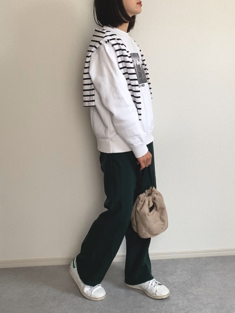 ホワイト系のスウェット、グリーン系のスラックス、ベージュ系のハンドバッグを着用したレディースの春コーディネートの2枚目の写真
