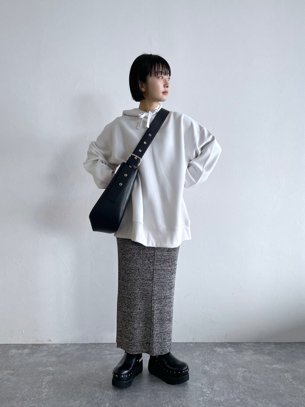 グレー系のスカート、ホワイト系のパーカー、ブラック系のショルダーバッグを着用したレディースの冬コーディネートの2枚目の写真