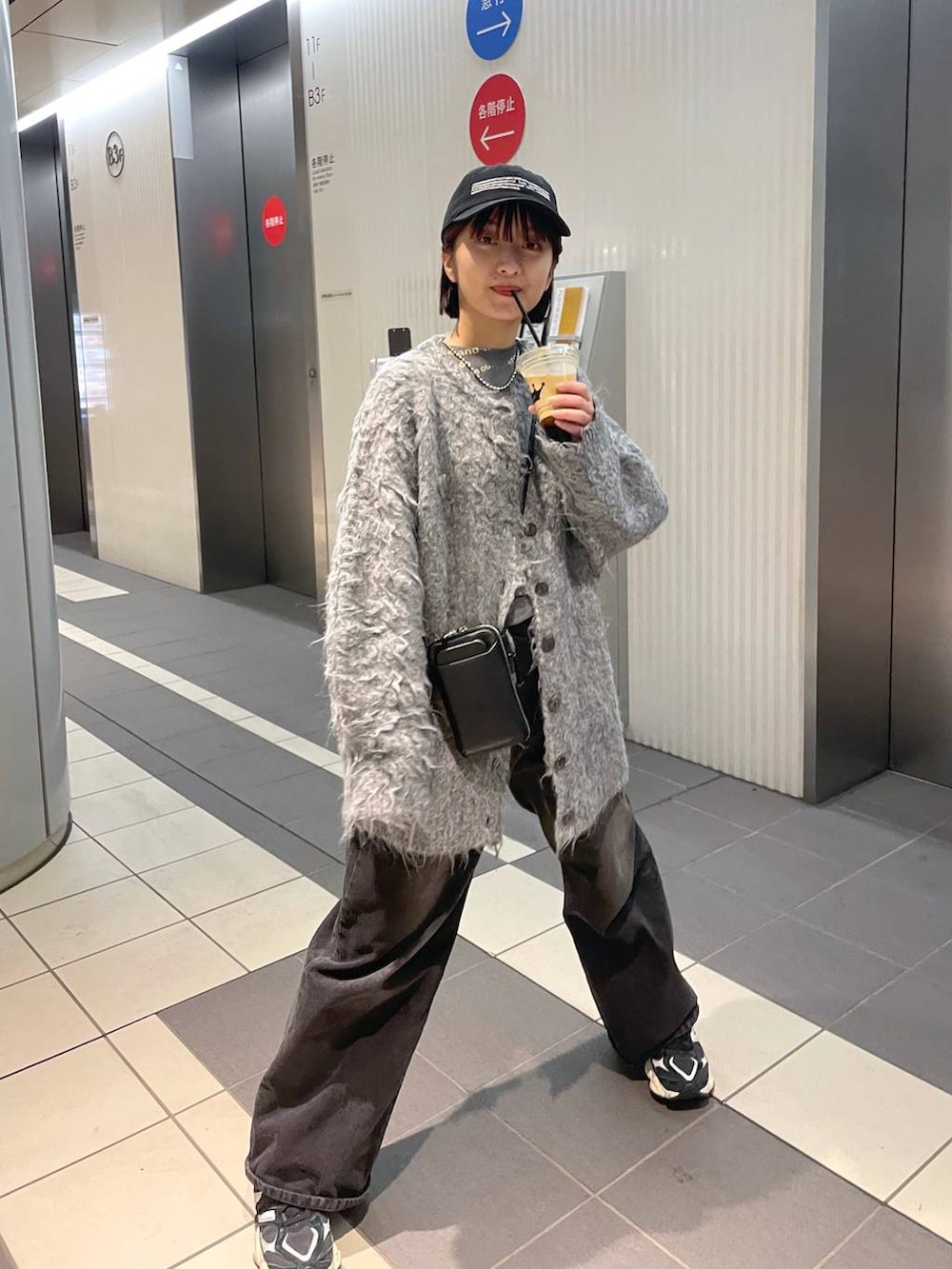 グレー系のTシャツ/カットソー、グレー系のカーディガン/ボレロ、ブラック系のデニムパンツを着用したレディースの冬コーディネートの2枚目の写真