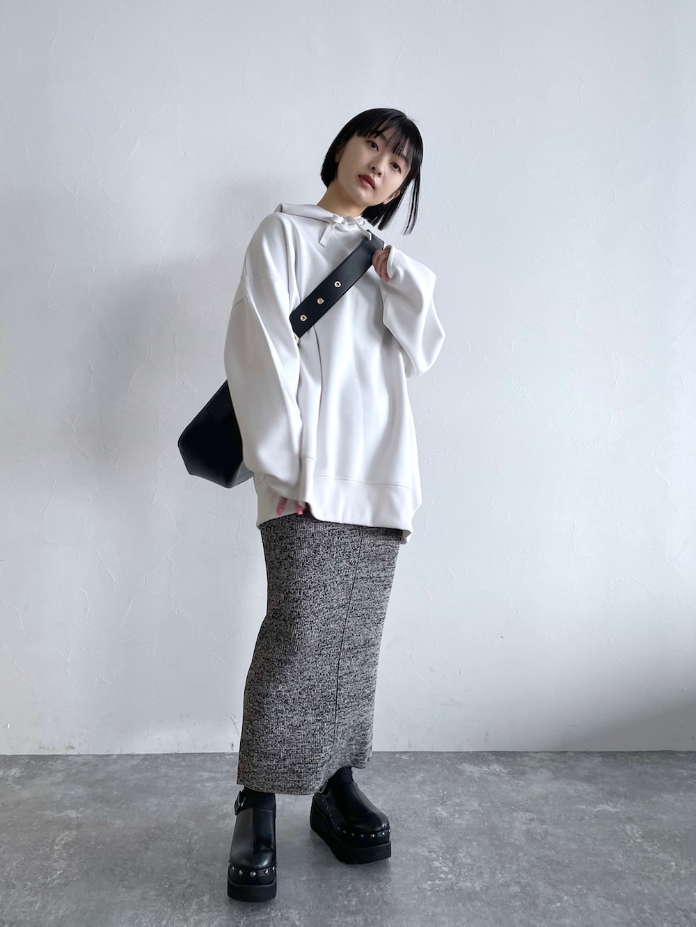 グレー系のスカート、ホワイト系のパーカー、ブラック系のショルダーバッグを着用したレディースの冬コーディネートの5枚目の写真