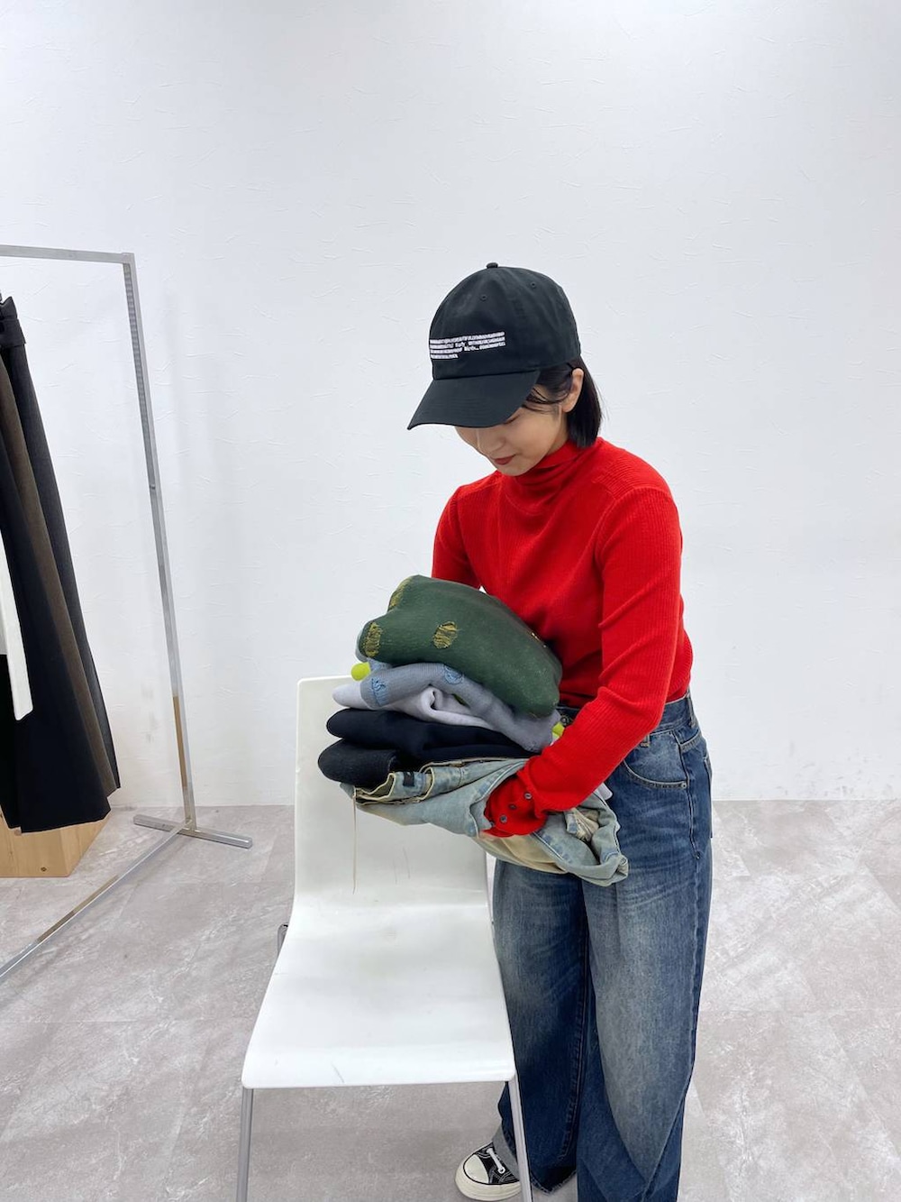 ブルー系のデニムパンツ、レッド系のニット/セーター、ブラック系のキャップを着用したレディースの秋コーディネートの3枚目の写真