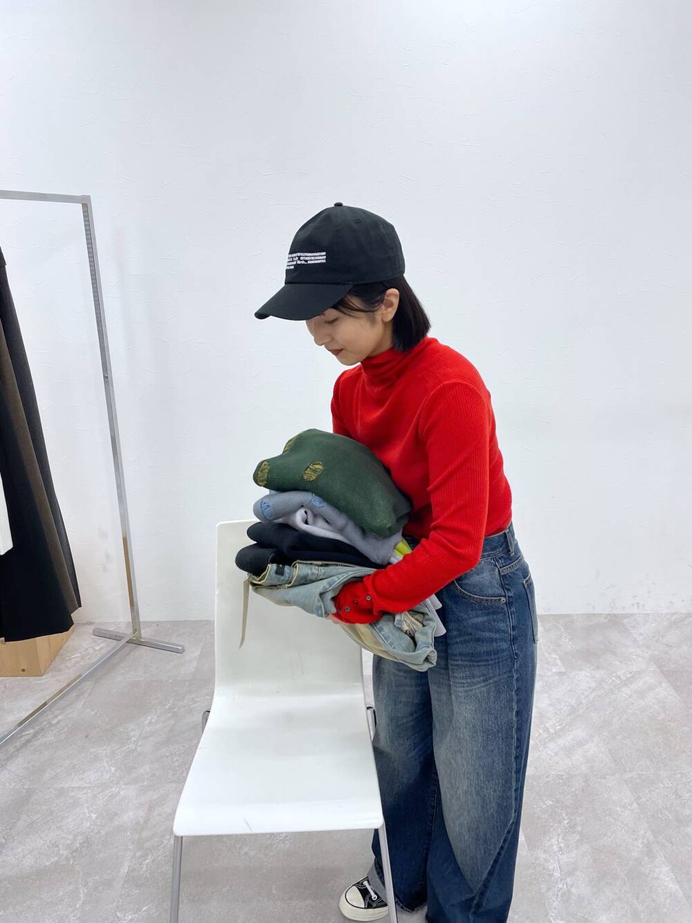 ブルー系のデニムパンツ、レッド系のニット/セーター、ブラック系のキャップを着用したレディースの秋コーディネートの2枚目の写真