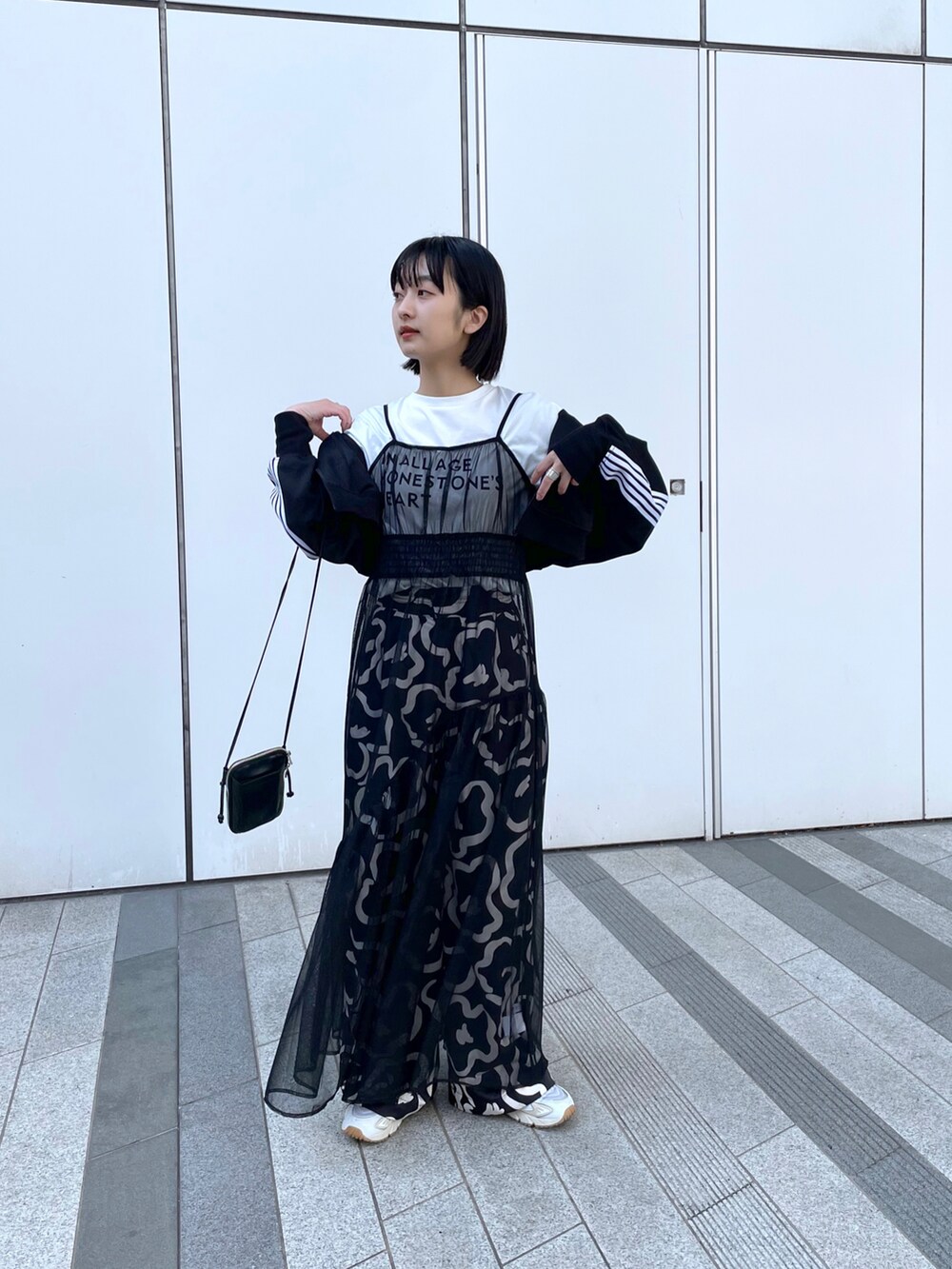 ブラック系のワンピース、ホワイト系のスニーカーを着用したレディースの春コーディネートの2枚目の写真