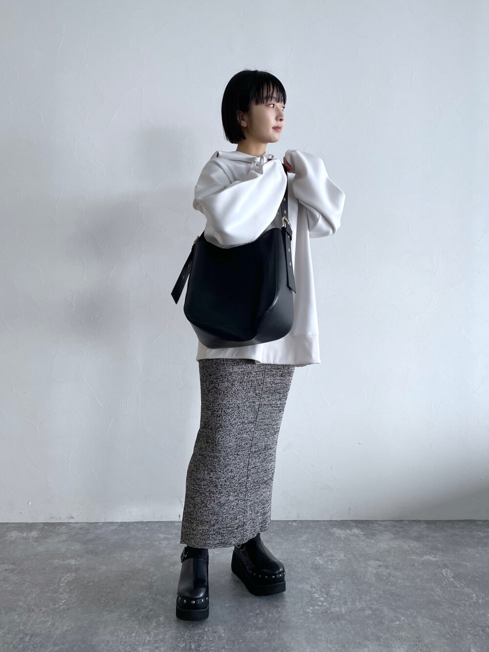 グレー系のスカート、ホワイト系のパーカー、ブラック系のショルダーバッグを着用したレディースの冬コーディネートの4枚目の写真