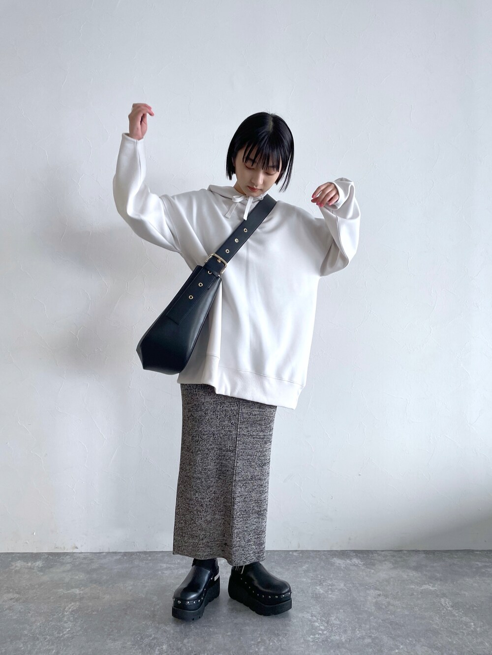 グレー系のスカート、ホワイト系のパーカー、ブラック系のショルダーバッグを着用したレディースの冬コーディネートの3枚目の写真