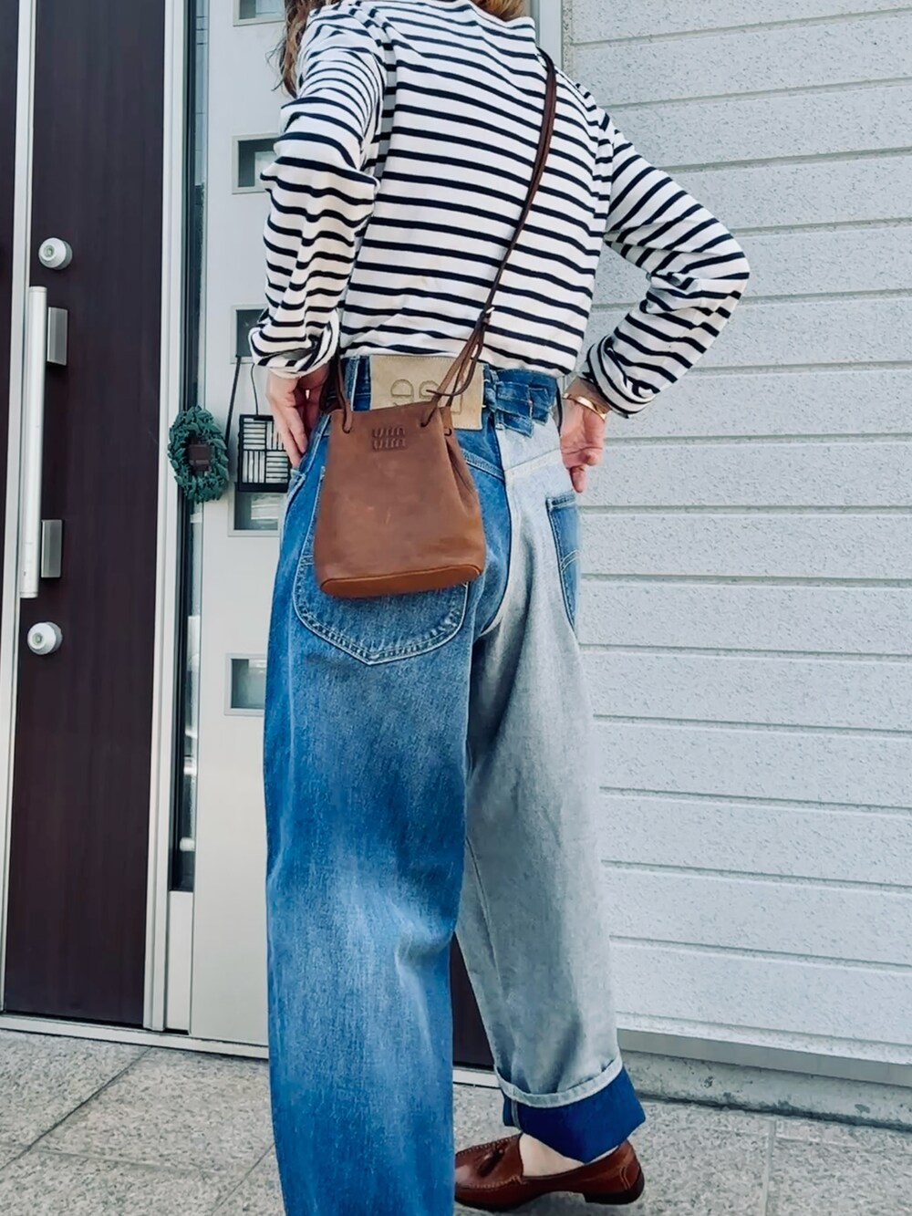 ブルー系のデニムパンツ、ブラウン系のショルダーバッグ、ベージュ系のTシャツ/カットソーを着用したレディースの春コーディネートの2枚目の写真